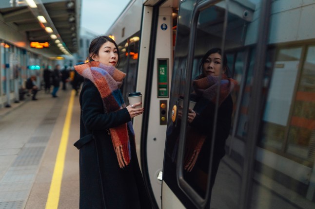 Young Asian woman getting on the train on railway platform