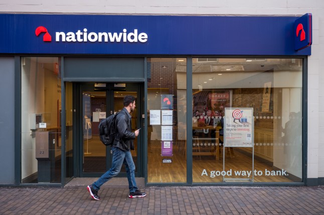 A man walking past a Nationwide building society branch on a UK high street, Middlesborough.