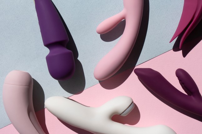 Collection of different types of sex toys on a blue and pink background. Sex toys for adults, dildos, vibrators, clitoral stimulators.