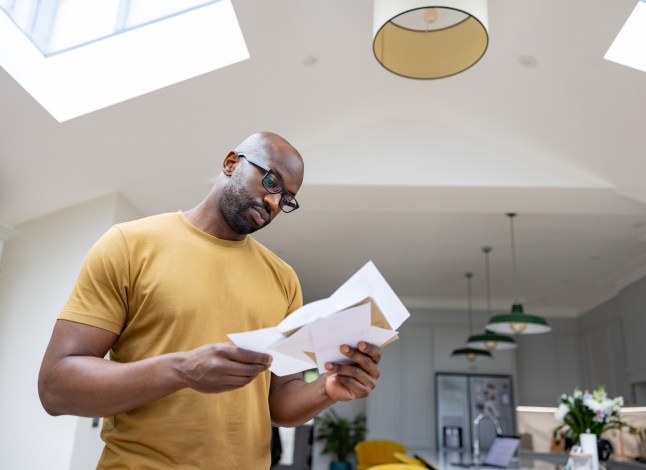Man at home reading a letter in the mail