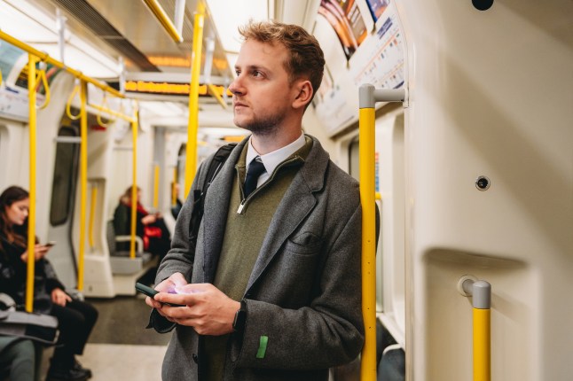 Businessman commuting on the London Underground holding a smartphone
