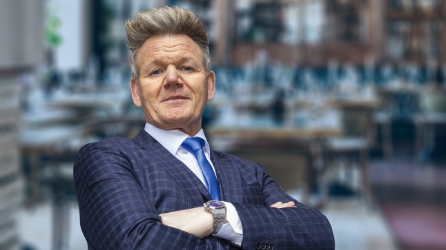 Gordon Ramsay wearing suit and blue tie crossing his arms.