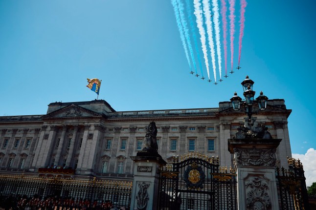 Nine Red Arrows jets trailing a Union Jack smoke pattern in the sky above Buckingham Palace.