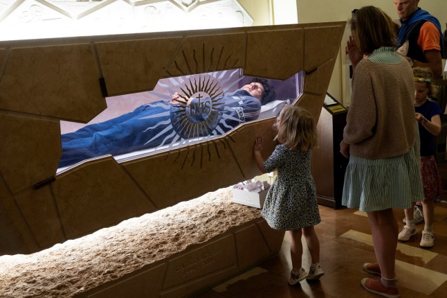 SENSITIVE MATERIAL. THIS IMAGE MAY OFFEND OR DISTURB A child looks at the tomb of Carlo Acutis, who died of leukemia in 2006 aged 15, in the Shrine of the Stripping of Church of Santa Maria Maggiore in Assisi, Italy, April 10, 2025. Pope Francis has cleared the way for Acutis to be the first saint of the millennial generation. REUTERS/Remo Casilli