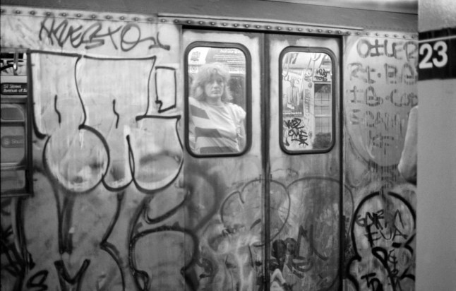 View, through the window of a graffiti-covered subway car, of a passengers at the 23rd street station, New York, New York, 1987. (Photo by Rita Barros/Getty Images)
