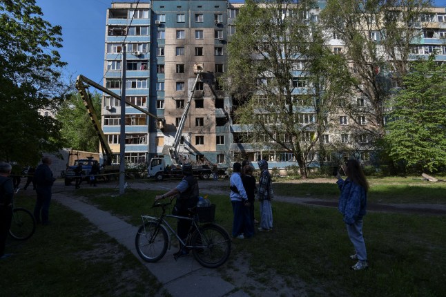 Residents stand near an apartment building hit by a Russian drone strike, amid Russia's attack on Ukraine, in the town of Kamyanske in Dnipropetrovsk region, Ukraine April 26, 2025. REUTERS/Mykola Synelnykov