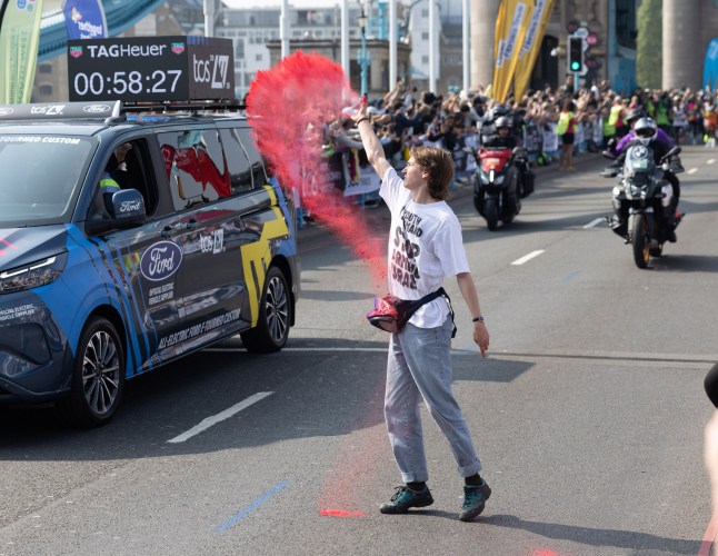 ? Licensed to London News Pictures. 27/04/2025. London, UK. A Youth Demand activist throws red powder as the men's Elite runners reach Tower Bridge during the London Marathon. Over 56,000 elite, fun and charitable runners tackle the 26. 2 miles across London, raising millions of pounds for charity. Photo credit: Peter Macdiarmid/LNP